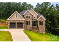 Charming brick two-story home featuring a two-car garage and lush green landscaping at 240 Mark Ryan Ln, Dallas, NC 28034