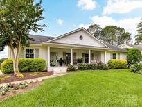 Charming single-story home with white painted brick, columns, and inviting front porch with beautiful landscaping at 2636 Chilton Pl, Charlotte, NC 28207