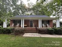 Charming brick home featuring a welcoming front porch with rocking chairs and classic white columns at 360 S Brady Ave, Newton, NC 28658