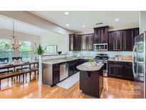 Modern kitchen featuring dark wood cabinets, granite countertops, and stainless steel appliances with hardwood flooring at 5056 Crandon Rd, Fort Mill, SC 29707