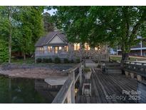 Waterfront home with a wooden dock, stone facade, and covered deck offering picturesque lakeside living at 639 Panther Point Trl, Richfield, NC 28137