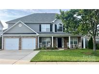 Charming two-story home with a well-manicured lawn, stone accents, and rocking chairs on the front porch at 107 Millen Dr, Mooresville, NC 28115