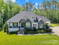 Charming home featuring a stone and white brick facade, landscaped yard, and inviting front porch at 2122 Goose Creek Farm Ln, Indian Trail, NC 28079