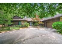 Charming home featuring a stone and siding exterior, lush landscaping, and a spacious driveway at 3041 Shallowood Ln, Charlotte, NC 28277