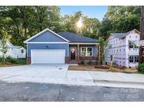 Charming blue house with a garage and brick accents on a sunny day, new construction at 354 Moore Ave, Mooresville, NC 28115