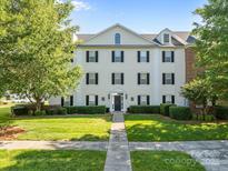 Attractive three-story condo with black shutters, manicured lawn, and lush green trees under a bright blue sky at 4024 Town Center Rd, Harrisburg, NC 28075