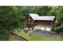 Beautiful log cabin exterior with stone accents, a metal roof, a lush lawn, and a patio area at 720 Potneck Rd, Salisbury, NC 28147