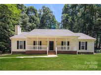 Charming single story home featuring a welcoming front porch, well-manicured lawn, and mature trees at 9000 Vagabond Rd, Charlotte, NC 28227