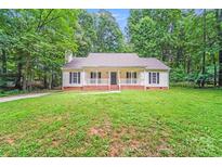Charming home features a welcoming front porch and a spacious, well-maintained lawn, surrounded by lush trees at 9000 Vagabond Rd, Charlotte, NC 28227