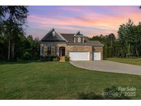 Brick home featuring a three-car garage, well-manicured lawn, and professional landscaping at 11226 Dappled Light Trl, Charlotte, NC 28227