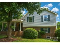 Charming two-story home featuring a covered front porch, lush landscaping, and a well-maintained lawn at 12431 Agate Ln, Pineville, NC 28134