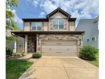 Two-story home featuring a stone facade, a two-car garage, a manicured lawn, and a welcoming covered front porch at 1314 San Gabriel Ave, Charlotte, NC 28214