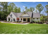 Beautiful home with a modern farmhouse design, green lawn, and mature trees at 176 Windwood Ln, Troutman, NC 28166