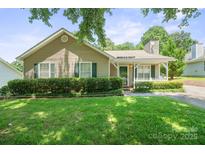 Charming single-story home with well-manicured lawn and cozy front porch with white picket fence at 322 Cottonwood Park Dr, Charlotte, NC 28214