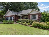 Charming brick home featuring a manicured front yard and lush landscaping, and mature trees in a desirable neighborhood at 43 Paddington Sw Dr, Concord, NC 28025