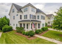 Charming two-story home featuring a covered front porch, manicured lawn, and mature landscaping at 5256 Meadowcroft Way, Fort Mill, SC 29708