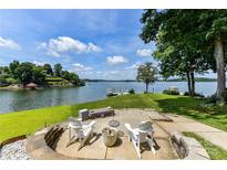 Beautiful backyard patio area with stone fire pit and Adirondack chairs overlooking the water at 7010 Coventry Ct, Tega Cay, SC 29708