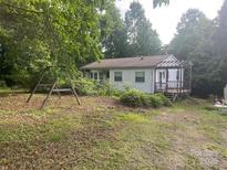 Quaint one-story home with a swing and covered porch nestled among mature trees in a serene setting at 9314 Seymour Ln, Davidson, NC 28036