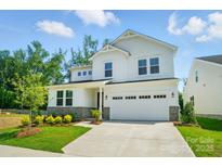 Charming two-story home featuring white siding, stone accents, manicured landscaping, and an attached two-car garage at 9846 Quercus Ln, Huntersville, NC 28078