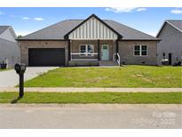 Charming, single-story home with brick exterior, blue door, black garage door, and well-maintained lawn at 103 Wadesborough Pl, Wadesboro, NC 28170