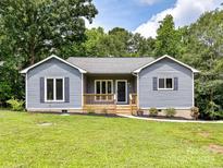 Charming blue home with a lovely wooden porch and well-manicured lawn, set against a backdrop of lush trees at 1117 Hidden Brook Ln, Clover, SC 29710