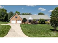 Charming brick home features a manicured lawn, a wide driveway, and an attached two-car garage at 139 Hardwick Dr, Mooresville, NC 28115