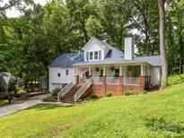 Charming white home with inviting front porch, brick accents, and lush greenery at 6934 Loretta Pl, Charlotte, NC 28215