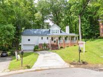 Charming two-story home with a welcoming front porch and well-maintained landscaping in a lush, green neighborhood at 6934 Loretta Pl, Charlotte, NC 28215