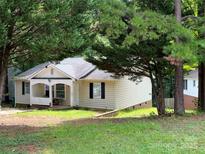 Charming single-story home featuring a cozy front porch and a well-maintained lawn surrounded by mature trees at 7015 Ware Rd, Charlotte, NC 28212