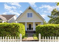 Charming yellow home featuring a gabled roof, inviting front porch with white columns and beautiful landscaping at 7344 Gilead Rd, Huntersville, NC 28078
