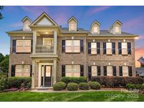 Beautiful brick two-story home with dormers, black shutters and mature landscaping at 7903 Tottenham Ct, Waxhaw, NC 28173