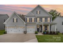 Beautiful two-story home featuring gray siding, black shutters, a three-car garage, and well-maintained landscaping at 808 Dogwood Creek Ln, Indian Trail, NC 28079