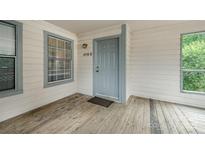 A welcoming entrance with a gray front door and windows to either side with a wooden porch at 8119 Tremaine Ct # E, Charlotte, NC 28227
