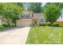 Charming two-story home featuring a well-manicured lawn, mature trees, and a two-car garage at 8701 Appaloosa Way Ln, Charlotte, NC 28216