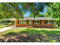 Charming brick home features a covered carport, manicured lawn, and classic black shutters at 113 Lou Dr, Gastonia, NC 28052
