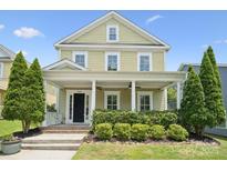 Charming two-story home with a welcoming front porch, manicured landscaping, and lush greenery at 12525 Druids Glen Dr, Pineville, NC 28134
