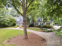 An exterior view of a beautiful home with mature landscaping and a circular driveway at 2032 Greenbrook Pkwy, Matthews, NC 28104