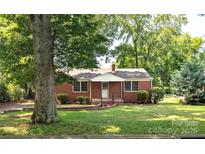 Charming single story brick home featuring a well manicured lawn and mature trees at 309 Fannie Cir, Charlotte, NC 28205