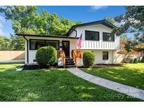 Charming renovated home featuring a white brick facade, black trim, lush landscaping, and inviting front entry at 4101 Tipperary Pl, Charlotte, NC 28215