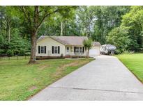 Charming home featuring a long driveway and a front yard surrounded by lush greenery and mature trees at 713 Hickory Hill Ct, Gastonia, NC 28054