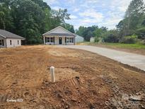 Charming single-story home featuring a manicured front yard and a concrete driveway, nestled amidst lush greenery at 812 Generation Ln, Clover, SC 29710