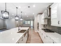 Modern kitchen featuring an island with a sink and white cabinetry, showcasing a sleek and functional design at 9662 Liberty Hill Dr, Mint Hill, NC 28227