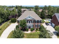 Stately brick home featuring a well-manicured lawn, mature trees, and an inviting front porch with columns at 11335 Wescott Hill Dr, Huntersville, NC 28078