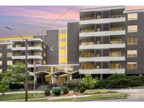 Multi-story building with brick facade, yellow accents, balconies, and landscaping at 1300 Reece Rd # 206, Charlotte, NC 28209