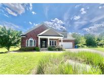 Charming red brick home with stone accents, covered porch, manicured lawn, and attached two-car garage at 1302 Devonmere Pl, Salisbury, NC 28144