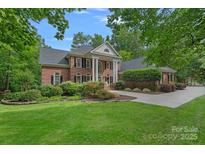 Stately brick home featuring elegant columns, manicured lawn, and mature landscaping at 1317 Longleaf Ct, Matthews, NC 28104