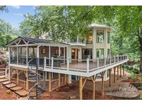 Expansive elevated deck featuring a screened porch and spiral staircase, surrounded by lush greenery and mature trees at 138 Ardmore Pl, Mooresville, NC 28117