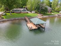 Aerial view showcases a lakefront home with a private covered boat dock and lush landscaping at 173 Riverwood Rd, Mooresville, NC 28117