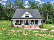 Charming home featuring a welcoming front porch with chairs and lovely landscaping at 4592 Reid Rd, Edgemoor, SC 29712