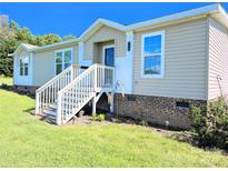 Charming manufactured home featuring a covered entry with white stairs and light beige siding on a sunny day at 4713 White Store Rd, Wingate, NC 28174